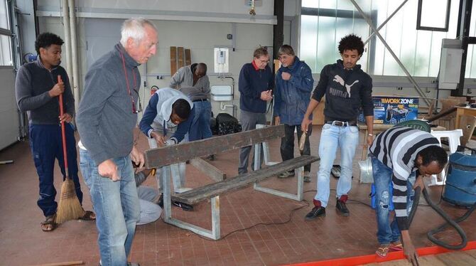 Projektstart in der Werkstatt:  Flüchtlinge arbeiten daran, alte Sitzbänke zu zerlegen. Aus den Brettern soll anschließend eine