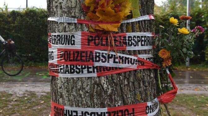 Der Tatort: Blumen sind mit einem Absperrband der Polizei an einem Baum in Freiburg befestigt.