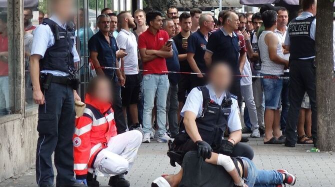 Polizisten nehmen am 24.07.2016 in Reutlingen (Baden-Württemberg) einen am Boden liegenden Mann fest, der zuvor eine Frau mit einer Machete getötet haben soll. Auf der Flucht hat er fünf Menschen verletzt.