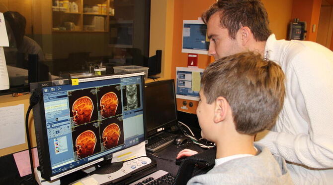 Ein Forscher zeigt auf dem undatierten Handout-Foto einem Kind Bilder von dessen Gehirn, die er zuvor mit einem Magnetresonanzto