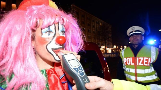 Ein als Clown verkleideter Fastnachtsnarr muss in Freiburg bei einer Alkoholkontrolle der Polizei in ein Messgerät pusten.