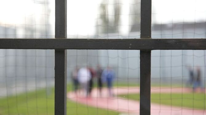Hinter einem Gitter laufen Gefängnisinsassen der Justizvollzugsanstalt in Stuttgart über einen Gefängnishof.