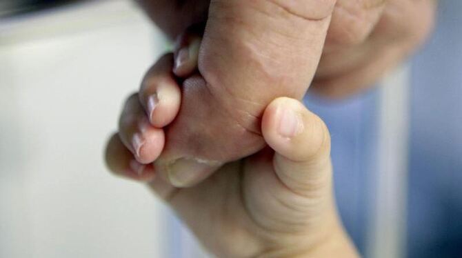 Die Hand eines Säuglings klammert sich an den Finger eines erwachsenen Mannes. Neugeborene werden statistisch gesehen heute m