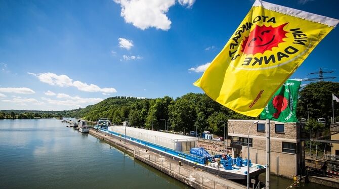 Demonstranten mit einer Fahne »Atomkraft Nein Danke« stehen auf einer Brücke, als das Transportschiff Edda mit noch leeren Behäl