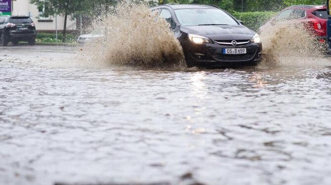 Ein Auto fährt in Bad Harzburg durch das Wasser der überfluteten Bundestraße B4. Foto: Swen Pförtner