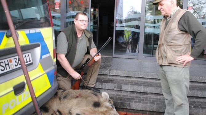 Ein Jäger kniet neben dem von ihn erlegten Wildschwein vor einer Sparkassen-Filiale in Heide. Foto: Helge Holmson