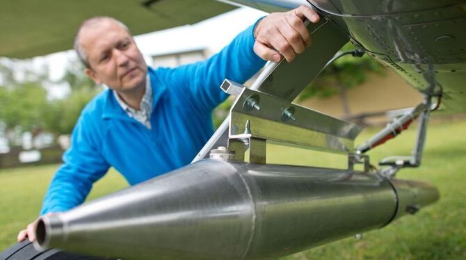 Klar zum Gefecht: Ein Pilot prüft den Rauchgasgenerator, mit dem er Gewitterwolken mit Silberjodid impft. FOTO: DPA Klar zum Gefecht: Ein Pilot prüft den Rauchgasgenerator, mit dem er Gewitterwolken mit Silberjodid impft. FOTO: DPA