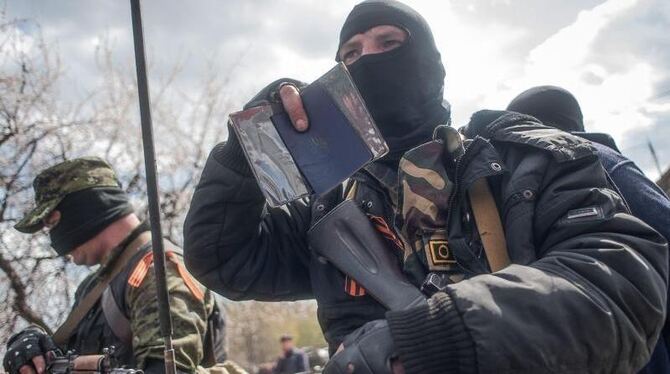 Ein Bewaffneter weist sich im ostukrainischen Slawjansk mit seinem Pass als Ukrainer aus. Foto: Roman Pilipey