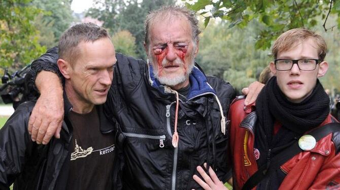 Zwei Männer stützen im Schlossgarten in Stuttgart den durch einen Wasserwerfer verletzten Dietrich Wagner. Foto: Marijan Mura