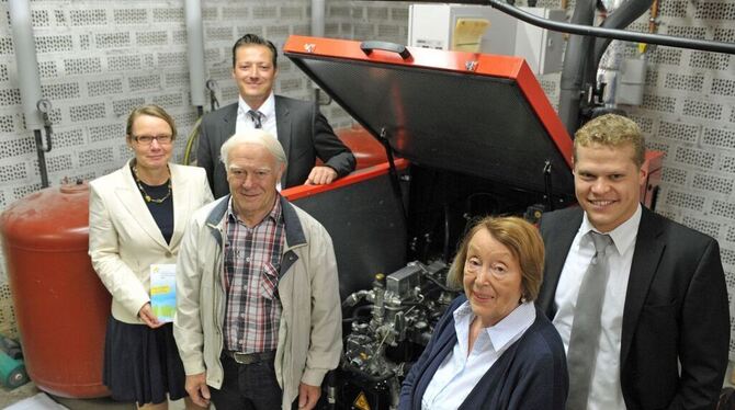 Gruppenbild mit Blockheizkraftwerk-Motor (von links): Katrin Korth (Amt für Tiefbau, Grünflächen und Umwelt), Michael Fuchs (hin