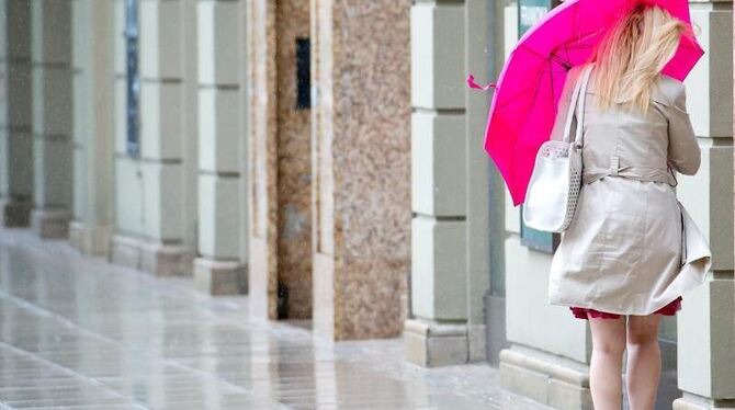Eine Frau kämpft in München mit ihrem Regenschirm gegen Wind und Regen. Foto: Sven Hoppe/Archiv