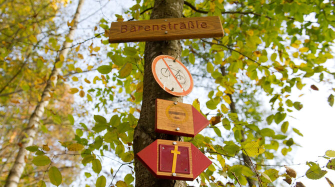 Ein rotes Schild mit einem gelben Kreuz (unten), das einen Pilgerweg markiert, hängt in der Nähe des Bärenschlössle in Stuttgart