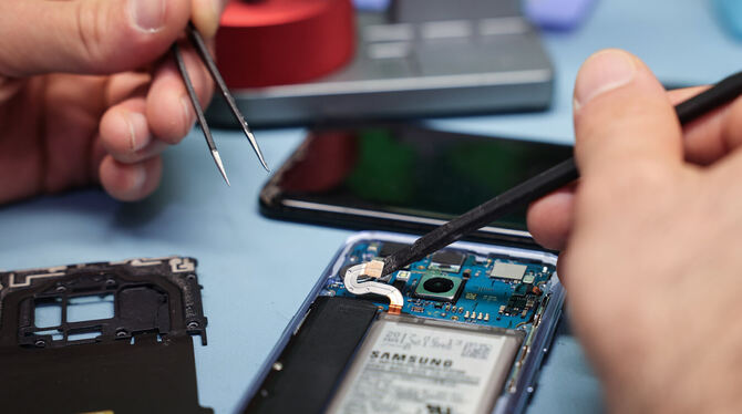 Ein Techniker repariert das Display eines Smartphones.