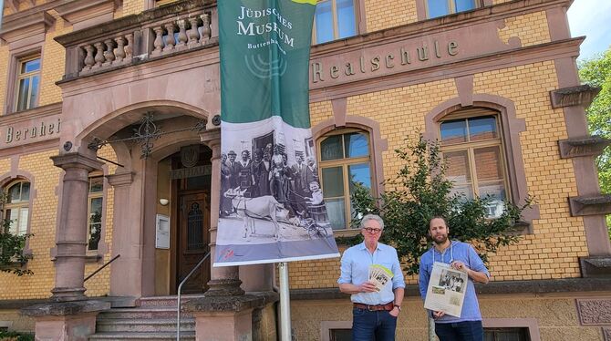 Stefan Hartmaier (links) und Yannik Krebs stellen die neu gestalteten Flyer, Plakate und Fahne zur Bewerbung des Jüdischen Museu
