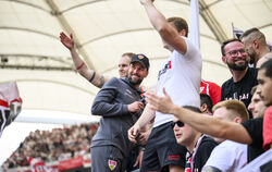 Stuttgarts Trainer Sebastian Hoeneß (grauer Anzug)  jubelt nach dem Spiel auf dem Zaun mit den VfB-Fans.