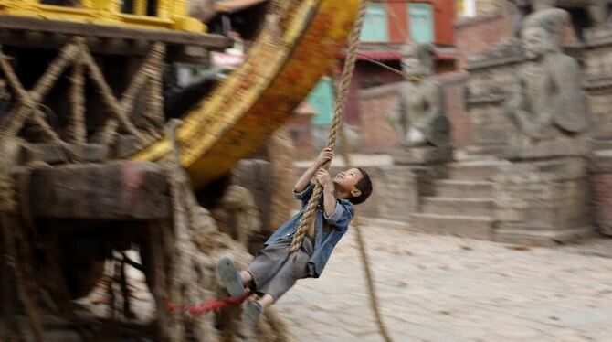 Er schaukelt inmitten seiner zerstörten Heimatstadt: Ein nepalesischer Junge amüsiert sich zwischen den Trümmern eines zerstö