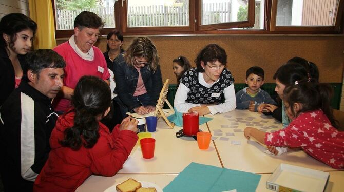 Annette Krauth (Mitte) spielt im Pfullinger Asylcafé mit Kindern, während Dolmetscherin Dijana Simegi (links, im pinkfarbenen Sh