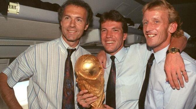 Rückflug mit Pokal: Franz Beckenbauer, Lothar Matthäus und Andreas Brehme reisen nicht mit leeren Händen von der WM ab. Foto: