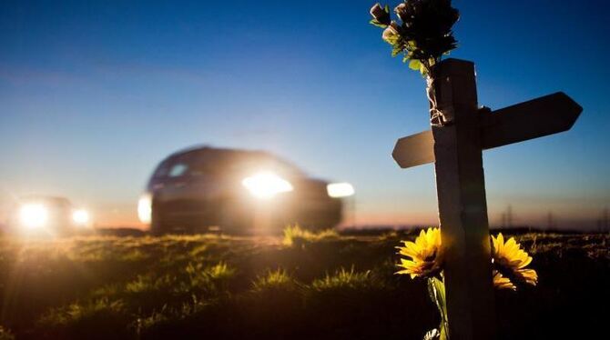 Ein Kreuz und Blumen erinnern am Straßenrand an einen Verkehrstoten. Foto: Julian Stratenschulte
