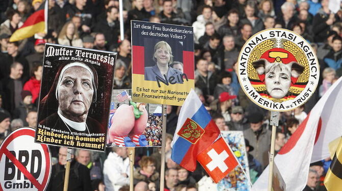 Anhänger von Pegida zeigen, was sie von Angela Merkel halten.