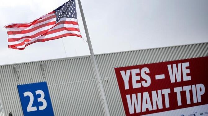 Eine amerikanische Flagge weht auf dem Gelände der Hannover Messe vor einem Plakat mit der Aufschrift »Yes - We want TTIP«. F
