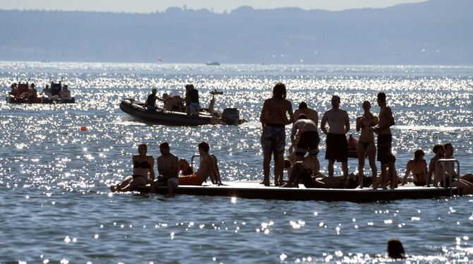 Badegäste sonnen sich vor Friedrichshafen auf einem Floß im Bodensee. Foto Felix Kästle/dpa