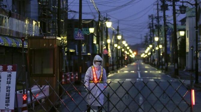 Ein Wachmann vor einer abgesperrten Straße unweit der Reaktorruine von Fukushima. Foto: Kimimasa Mayama