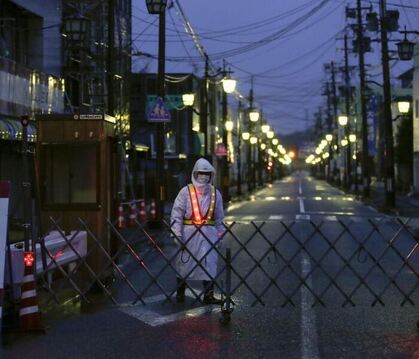 Ein Wachmann vor einer abgesperrten Straße unweit der Reaktorruine von Fukushima. Foto: Kimimasa Mayama