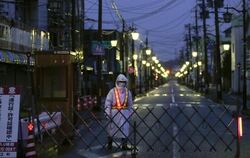 Ein Wachmann vor einer abgesperrten Straße unweit der Reaktorruine von Fukushima. Foto: Kimimasa Mayama