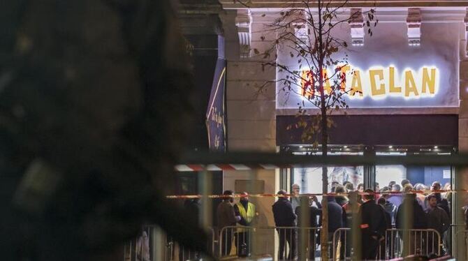 Geschützt durch Polizisten haben sich am Samstagabend Konzertbesucher zur Wiedereröffnung des Bataclan versammelt. Foto: Ian