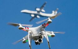 Eine private Drohne fliegt über einem Garten, während in einiger Entfernung ein Flugzeug beim zu sehen ist. Foto: Julian Stra