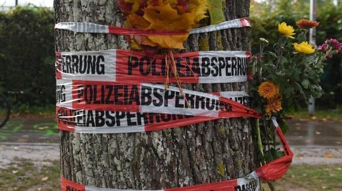Blumen sind mit einem Absperrband der Polizei an einem Baum in Freiburg befestigt. Foto: Patrick Seeger/Archiv