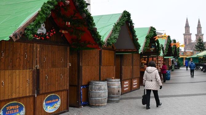 Passanten gehen in Ludwigshafen an den geschlossenen Ständen des Weihnachtsmarktes vorbei.