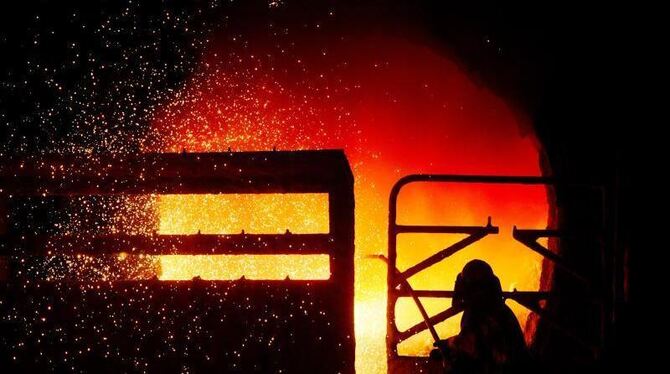 Ein Stahlarbeiter säubert eine noch glühende Stahlpfanne. Foto: Julian Stratenschulte/Illustration