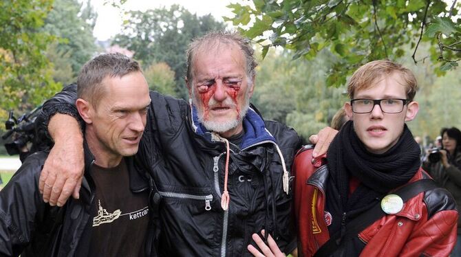Zwei Männer stützen im Schlossgarten in Stuttgart den durch einen Wasserwerfer verletzten Dietrich Wagner nach einer Demonstrati