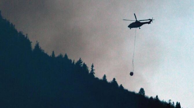 Hubschrauber mit Löschwasservorrichtung über dem Jochberg oberhalb von Kochel am See. Foto: Peter Kneffel