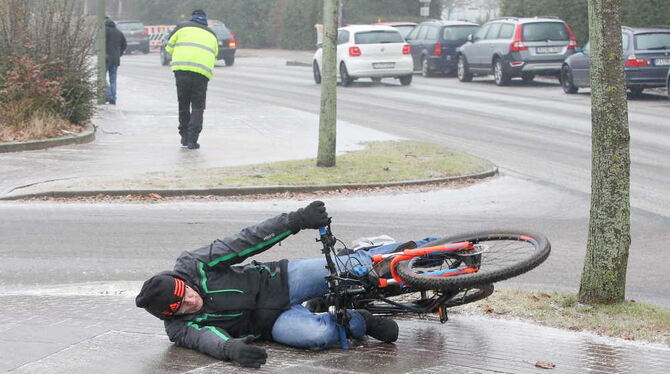 Ein Fahrradfahrer liegt bei extremer Glätte auf einem Radweg, nachdem er zuvor ausgerutscht war. Spiegelglatte Wege im Norden ha