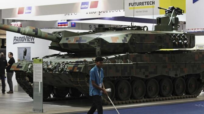 Ein Mann putzt auf der Internationalen Ausstellung für Verteidigung in Abu Dhabi vor dem Stand des deutschen Rüstungsunternehmen