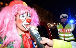 Ein als Clown verkleideter Fastnachtsnarr muss in Freiburg bei einer Alkoholkontrolle der Polizei in ein Messgerät pusten.