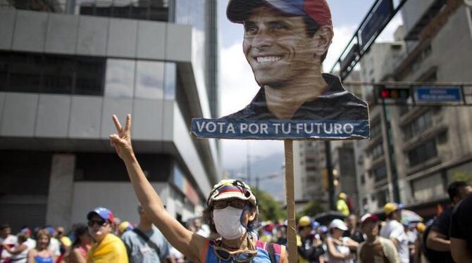 Eine Frau trägt ein T-Shirt und ein Plakat mit dem Konterfei des venezolanischen Oppositionsführers Henrique Capriles. Foto: