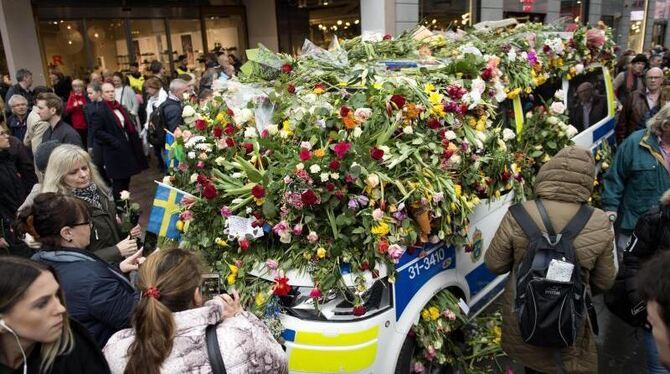 Ein Polizeifahrzeug ist in der Innenstadt von Stockholm nach dem mutmaßlichen Terroranschlag fast vollständig mit Blumen bede