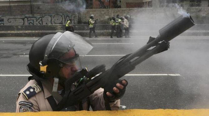 Ein Polizist feuert Tränengas in Richtung protestierender Demonstranten. Foto: Fernando Llano