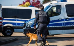 Einsatz in Rottenburg: Ein Polizist läuft mit einem Polizeihund an Polizeieinsatzfahrzeugen vorbei.