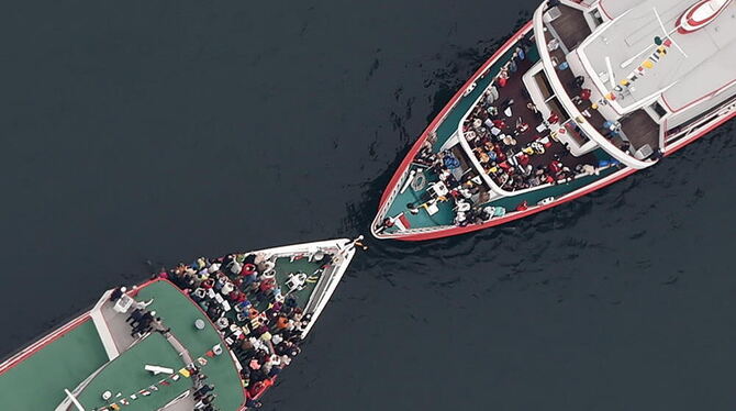 Zwei Passagierschiffe nähern sich auf dem Bodensee vor Konstanz so sehr, dass sich die Kapitäne der jeweiligen Schiffe vom Bug a Zwei Passagierschiffe nähern sich auf dem Bodensee vor Konstanz so sehr, dass sich die Kapitäne der jeweiligen Schiffe vom Bug a