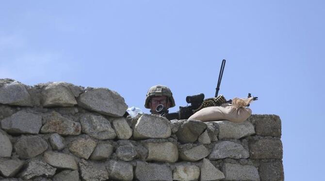 Ein US-amerikanischer Soldat in Asad Khil hält Wache hinter einer Steinmauer. Foto: Rahmat Gul/Archiv