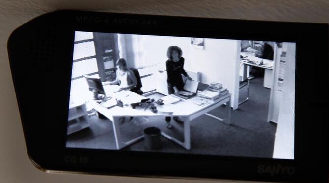 Eine Videokamera zeichnet in der gestellten Szene die Arbeit in einem Büro auf.