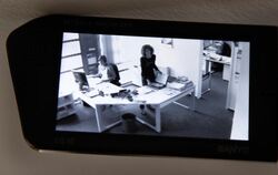 Eine Videokamera zeichnet in der gestellten Szene die Arbeit in einem Büro auf.