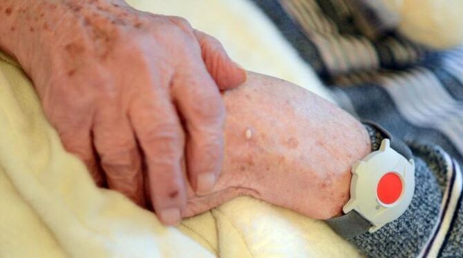 Eine pflegebedürftige Frau trägt einen Notknopf am Handgelenk. Foto: Britta Pedersen/Symbolbild