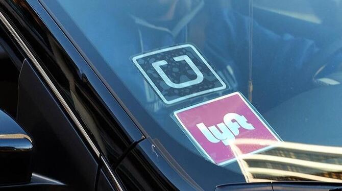 An der Scheibe eines Autos hängen Aufkleber der beiden Fahrdienst-Vermittler »Uber« und »Lyft«. Foto: Richard Vogel/Archiv