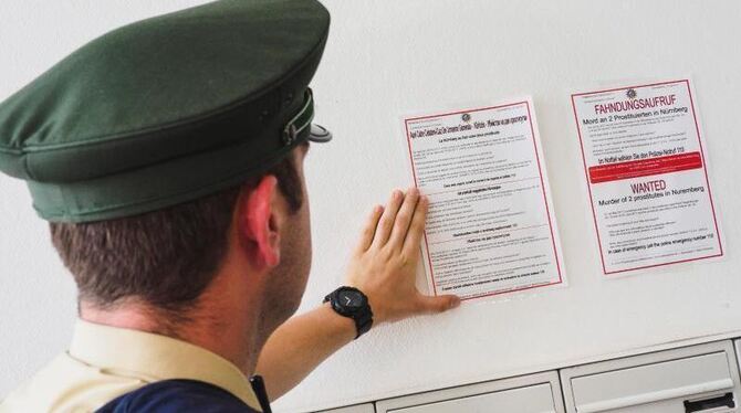 Ein Polizist klebt in Nürnberg in einem bordellähnlichen Etablissement einen Fahndungsaufruf in verschiedenen Sprachen an ein